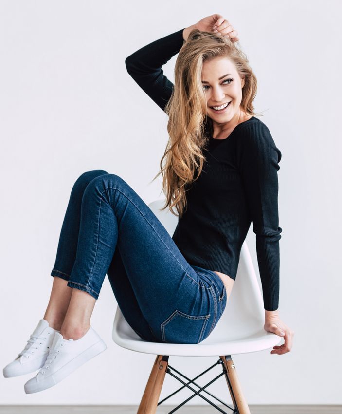  Lomita HydraFacial model sitting on a chair smiling