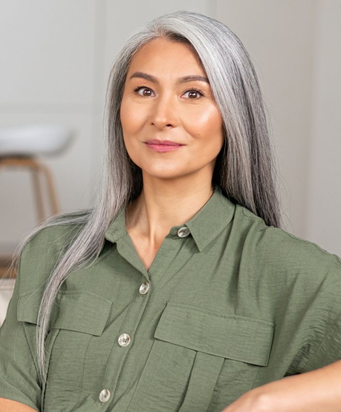 South Bay dermal fillers model with gray hair sitting on a couch