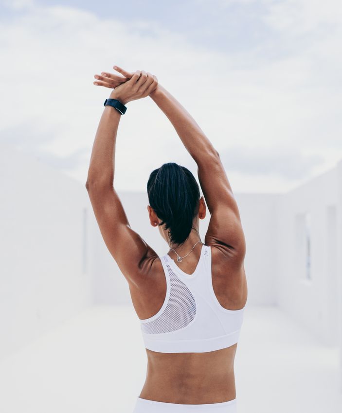 Palos Verdes microneedling model in a white sports bra stretching her body